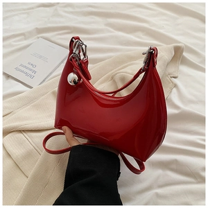 Vue détaillée du sac haricot en cuir verni rouge brillant avec pendentif boule argentée