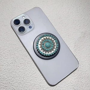 Macro detail of retro round phone grip with turquoise stone inlay and silver mandala pattern