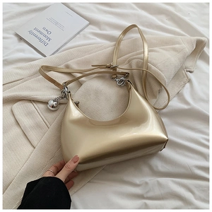 Détail du sac hobo doré brillant avec finition métallique et breloque boule argentée