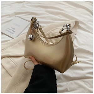 Détail du sac demi-lune doré champagne avec finition miroir et breloque argentée