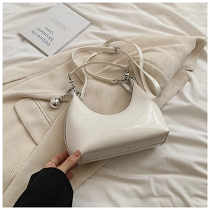 Détail d'un sac à bandoulière blanc crème brillant avec breloque boule argentée