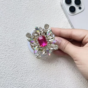 Detail view of luxurious rose red rhinestone flower MagSafe grip on a white phone base