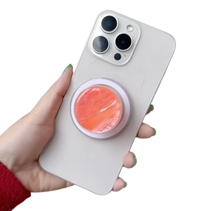 Foldable phone grip with orange marble pattern mounted on a white phone case held by hand