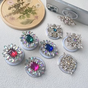 Detail of luxury rhinestone and pearl collapsible phone grip with variety of gem colors
