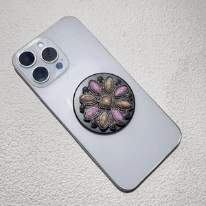 Detailed view of bohemian style round phone grip featuring pink stone floral inlay