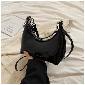 Détail d'un sac demi-lune en cuir verni noir brillant avec fermeture éclair argentée