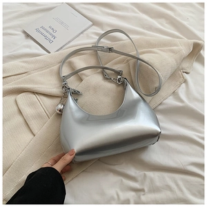 Détail d'un sac hobo argenté effet miroir avec une breloque décorative en boule métal