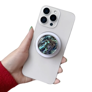 Detail view of iridescent abalone shell pattern phone socket grip on a white phone
