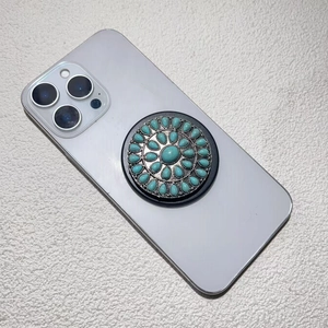 Close-up of retro silver phone grip with turquoise stones on a white mobile phone