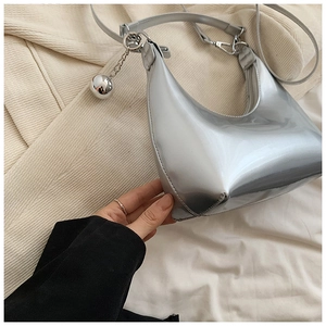 Détail d'un sac demi-lune argenté brillant avec charme en métal et bandoulière