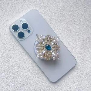 Close-up of luxury phone grip featuring blue gemstone, clear rhinestones and pearls