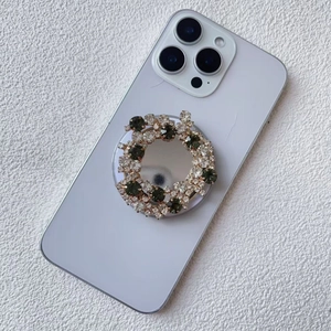 Macro shot of mirror-surface phone grip with luxury green and white rhinestones