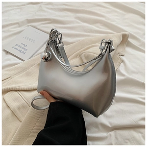 Détail du sac croissant argenté avec finition métallique brillante et grand charm sphérique