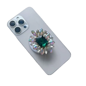 Luxury emerald gemstone phone socket with rhinestones on a blue smartphone