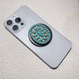 Detail of vintage electroplated phone grip with green turquoise stones on gray smartphone