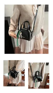 Détail du sac à main noir en forme de coquille avec bordure blanche et pendentif ours