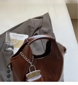 Detailed view of dark brown oil-leather tote bag with silver chain and mini pouch