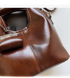 Close-up of brown oiled leather tote bag with metallic chain and matching mini pouch