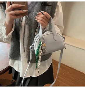 Détail du sac bowling bleu clair avec pendentif tressé et bandoulière réglable