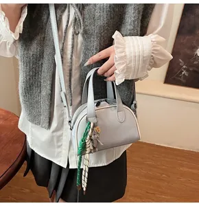 Détail du sac à main bleu clair avec logo YAZIANDI et pendentifs décoratifs