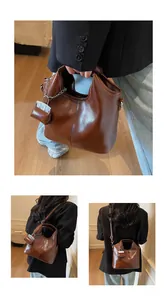 Detail view of dark brown vintage faux leather tote with matching mini pouch and strap