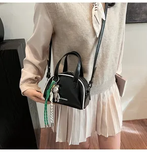 Détail du mini sac bandoulière noir avec passepoil blanc et accessoire pendentif ours