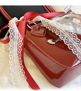 Detail of red patent leather ita bag with heart-shaped zipper and lace bow accents