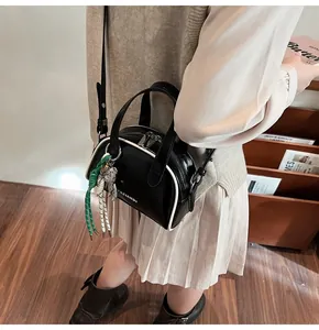 Vue détaillée du sac bowling en cuir verni noir avec logo YAZIANDI et pendentif ours