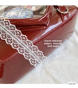 Detail of red patent leather ita bag showing precise stitching and heart-shaped lace trim