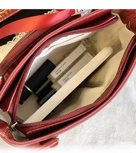 Internal compartment of wine red glossy bag showing phone and cosmetics storage