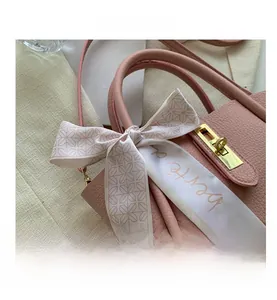 Détail du sac à main rose en cuir avec fermoir doré et foulard en soie décoratif
