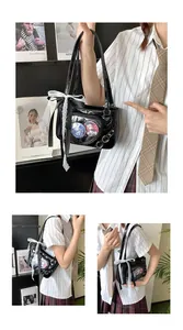 Detail of black ita-bag featuring a heart-shaped window and white lace bow decoration