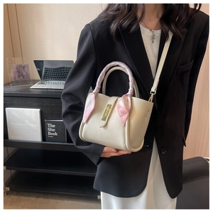 Détail d'un sac seau en cuir grainé crème avec poignée foulard et boucle dorée