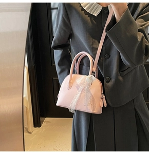 Détail du petit sac rose avec texture grainée et pendentif en dentelle élégant