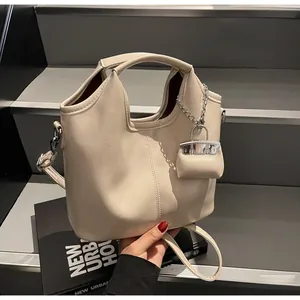 Detail of cream PU leather bucket bag with mini charm and silver hardware