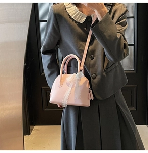 Sac à main rose grainé avec nœud en dentelle et bandoulière réglable sur le mannequin