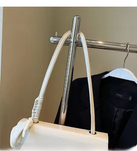 Minimalist white leather handbag detail showing smooth shoulder strap and silk scarf decor