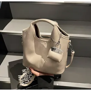 Detail of beige PU leather bucket tote with adjustable strap and mini charm accessory