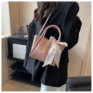 Détail du sac à main en cuir rose avec foulard en soie et fermoir en métal doré