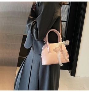 Modèle portant un petit sac rose pâle avec nœud en dentelle et texture grain lychee