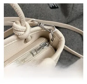 Detailed close-up of cream textured leather bag with silver metal zipper and lobster clasp