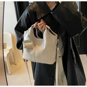 Detail of a creamy beige glossy leather tote bag with matching mini pouch and metal chain