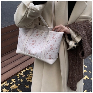 Close-up of white tote bag featuring cartoon animal prints and brand logo in autumn setting