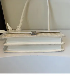 Detail of cream white leather bag with sparkling diamond buckle and silk scarf handle