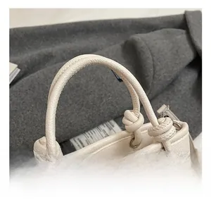 Detail of white lychee leather handbag featuring knotted rope handle and silver buckle