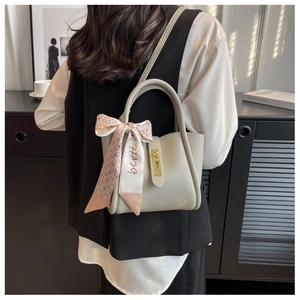 Détail du sac seau beige en cuir grainé avec foulard en soie et boucle dorée