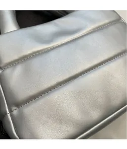 Detail of silver quilted PU leather texture with fine stitching on a puffy handbag
