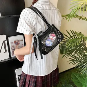 Detail of black ita bag with clear window, anime badges, lace trim, and ribbon bow