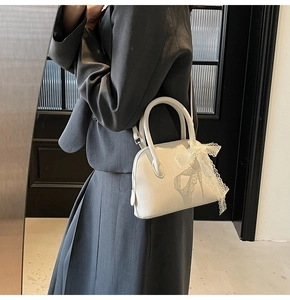 Détail du sac à main blanc en cuir grainé avec charm en dentelle et bandoulière réglable