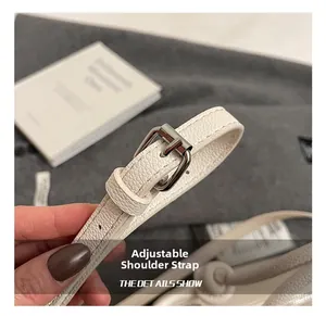 Detail of adjustable white lychee pattern leather shoulder strap with silver buckle